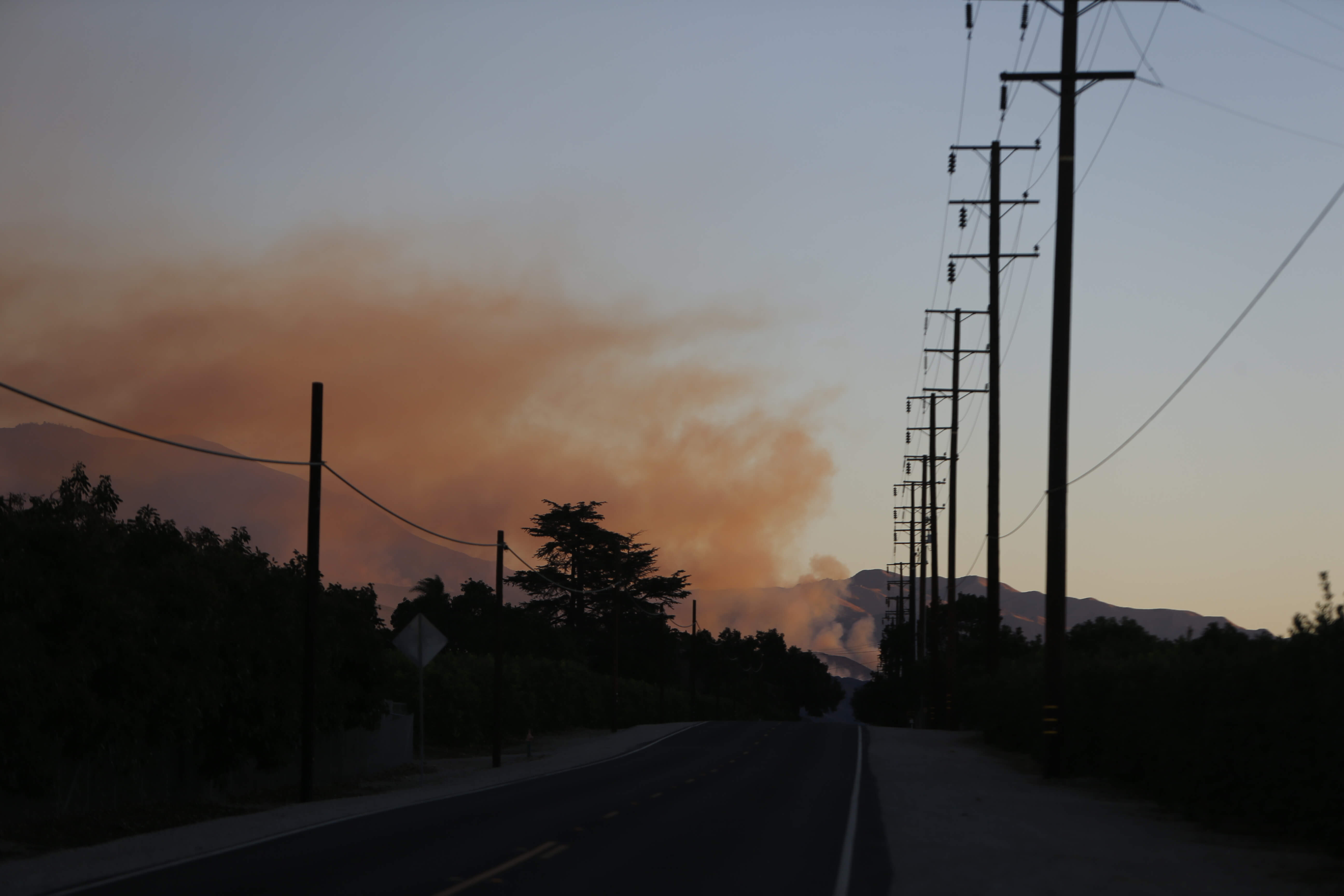 Utility poles near a wildfire at dusk