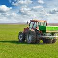 Tractor in field spreading fertilizer