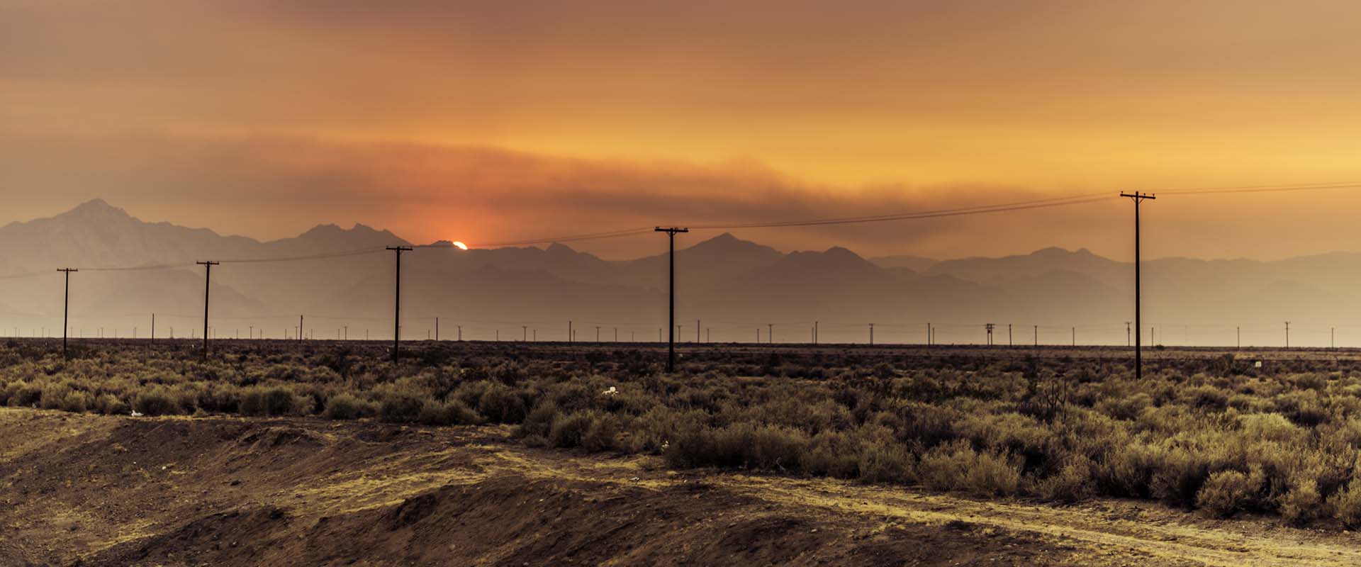 Wood power poles in mountains at sunset