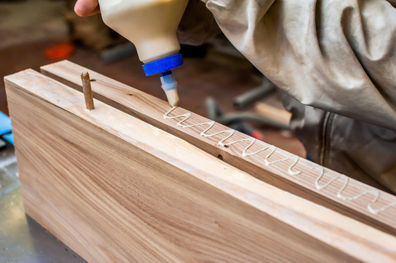 Carpenter applying wood glue to board