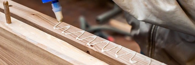 Carpenter applying wood glue to board